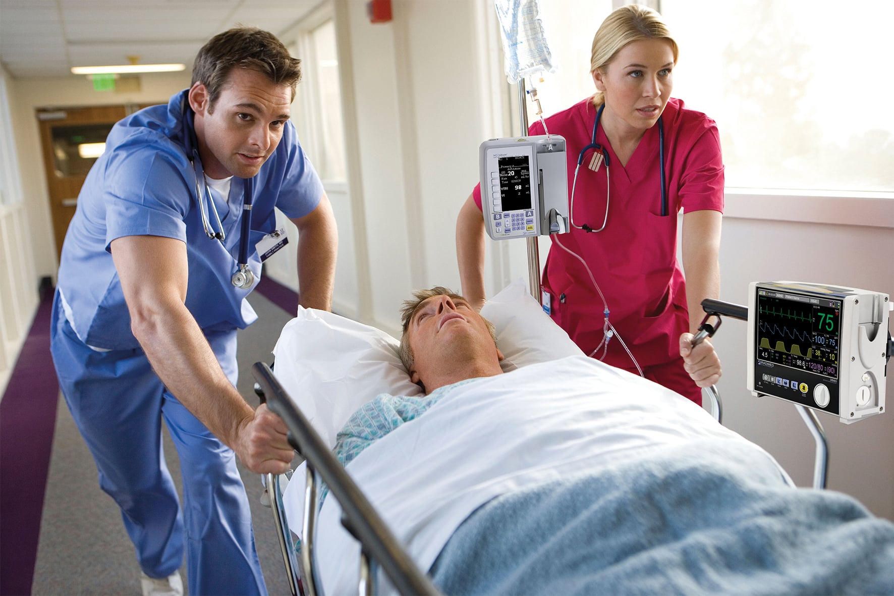 Patient on a infusion pump getting pushed by doctors in a hospital.